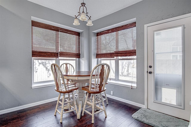 dining space with baseboards, a textured wall, wood-type flooring, an inviting chandelier, and a textured ceiling