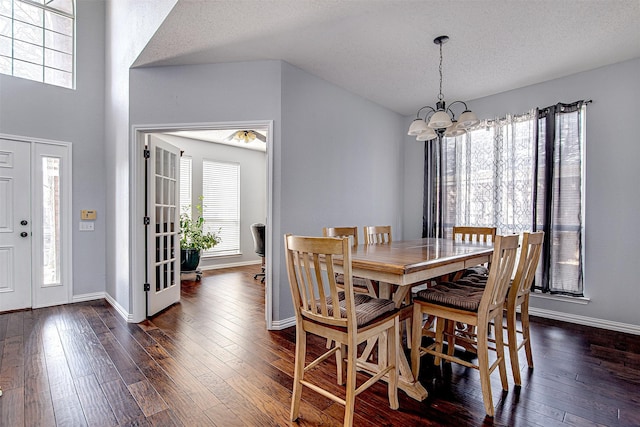 dining area featuring a notable chandelier, dark wood finished floors, a textured ceiling, and baseboards