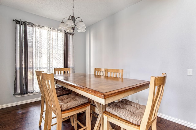 dining room with a textured ceiling, baseboards, dark wood finished floors, and a notable chandelier