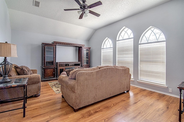 living area with light wood-type flooring, visible vents, and a wealth of natural light