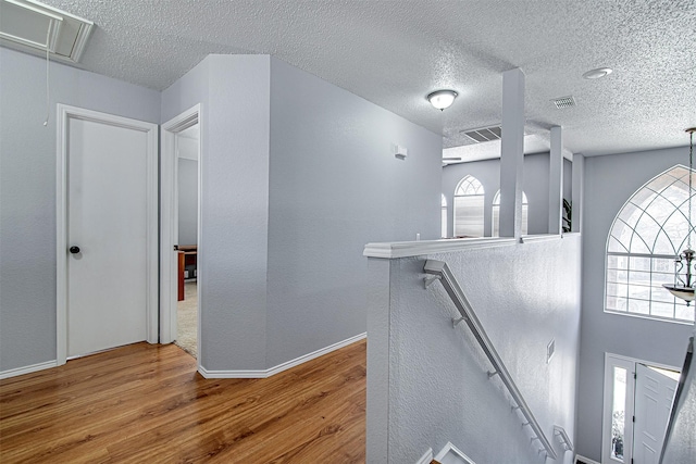 hallway featuring a healthy amount of sunlight, attic access, wood finished floors, and an upstairs landing