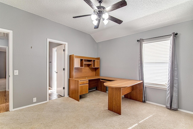 home office featuring light carpet, vaulted ceiling, a textured ceiling, ceiling fan, and baseboards