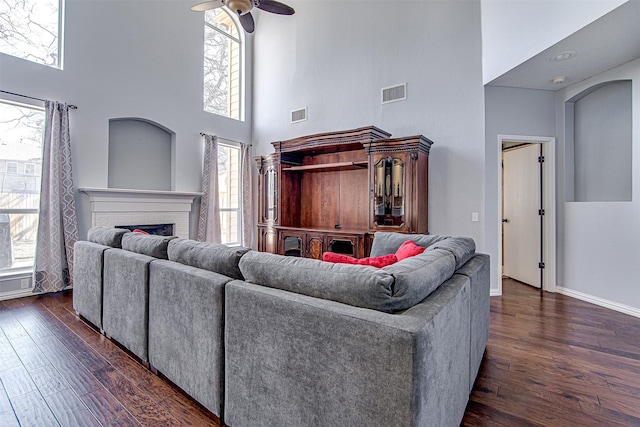 living room with a fireplace, visible vents, and dark wood-style flooring