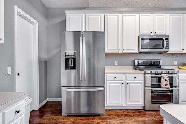 kitchen featuring light countertops, appliances with stainless steel finishes, dark wood-style flooring, and white cabinets