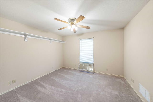 empty room with light carpet, ceiling fan, visible vents, and baseboards