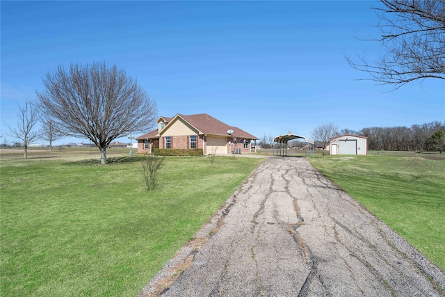 view of front facade featuring aphalt driveway, brick siding, an outdoor structure, a carport, and a front yard