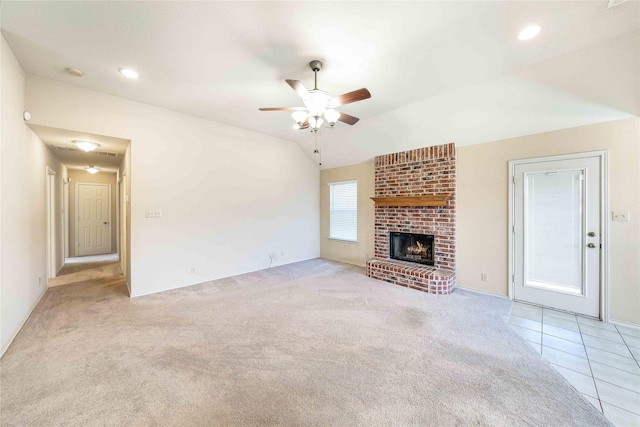 unfurnished living room featuring carpet, a fireplace, lofted ceiling, ceiling fan, and tile patterned flooring