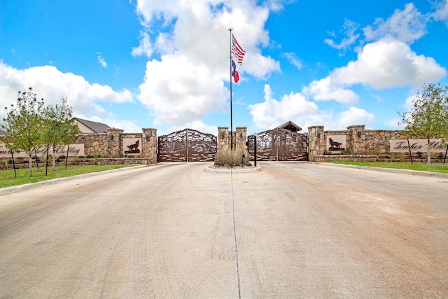 view of street with a gate, curbs, and a gated entry