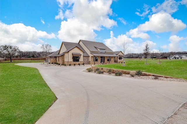 view of front of property with concrete driveway, stone siding, roof with shingles, a front lawn, and board and batten siding