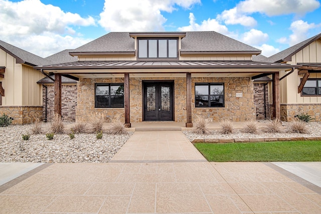 view of front of house featuring stone siding, a standing seam roof, a shingled roof, and french doors