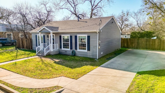 bungalow-style house featuring a front yard, fence, and a shingled roof