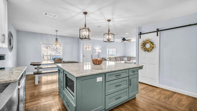 kitchen with baseboards, visible vents, dark wood finished floors, stainless steel appliances, and green cabinets