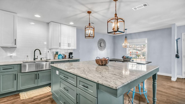 kitchen with a sink, visible vents, an inviting chandelier, and green cabinets