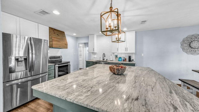 kitchen with a sink, light stone countertops, visible vents, and stainless steel appliances