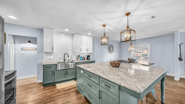 kitchen with visible vents, green cabinetry, a sink, white cabinets, and electric stove