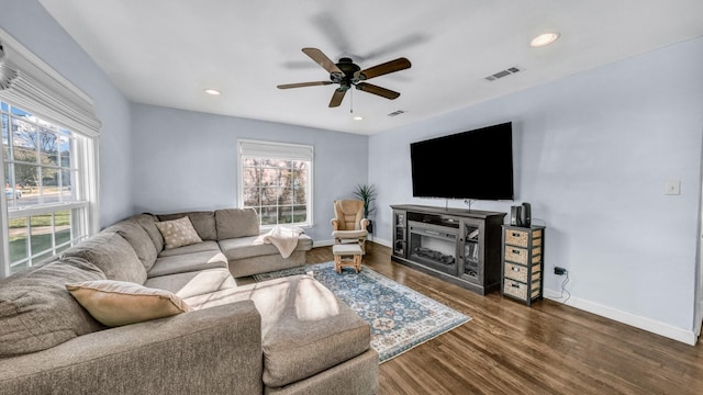 living area featuring plenty of natural light, baseboards, a ceiling fan, and dark wood-style flooring