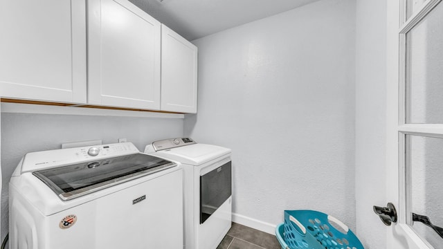 washroom featuring cabinet space, dark tile patterned flooring, baseboards, and separate washer and dryer