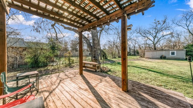 wooden terrace featuring a yard, an outbuilding, fence, and a pergola