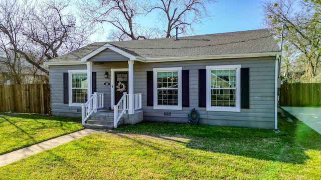 view of front of property with roof with shingles, a front yard, and fence