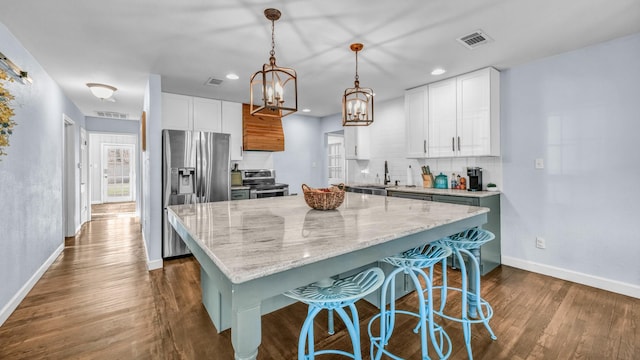 kitchen featuring visible vents, a sink, backsplash, appliances with stainless steel finishes, and dark wood-style flooring