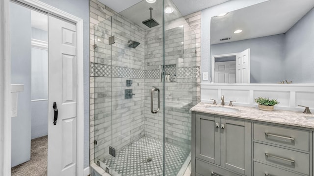 full bathroom featuring double vanity, visible vents, a shower stall, and a sink