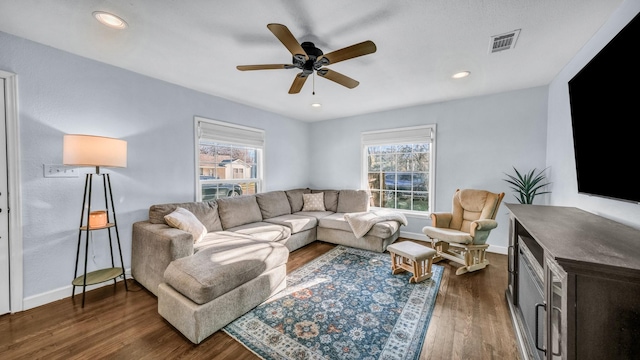 living room with dark wood finished floors, visible vents, baseboards, and ceiling fan