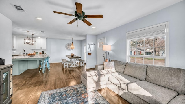 living room featuring visible vents, baseboards, dark wood finished floors, ceiling fan with notable chandelier, and recessed lighting