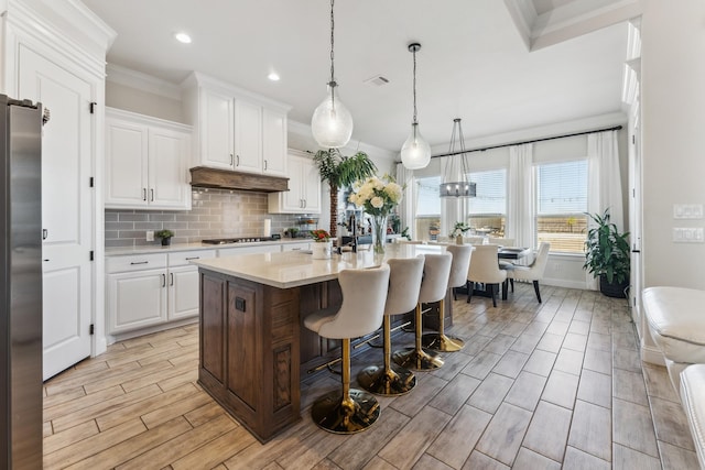 kitchen with light countertops, visible vents, decorative backsplash, appliances with stainless steel finishes, and under cabinet range hood