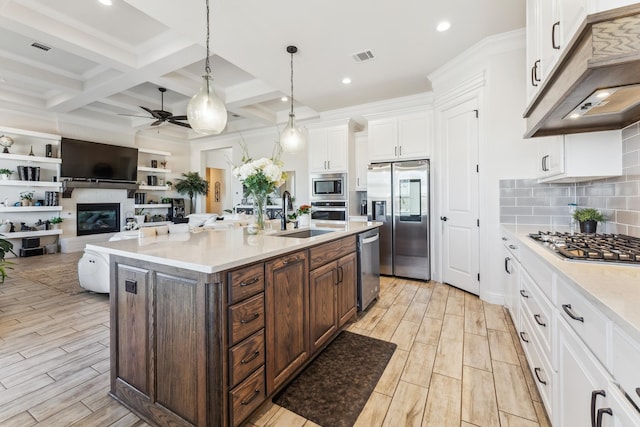 kitchen with white cabinets, appliances with stainless steel finishes, beamed ceiling, wood finish floors, and a sink