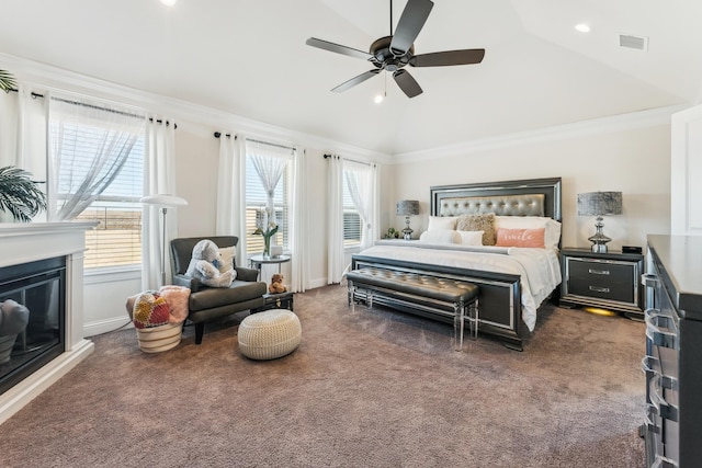 carpeted bedroom featuring ornamental molding, lofted ceiling, visible vents, and a glass covered fireplace