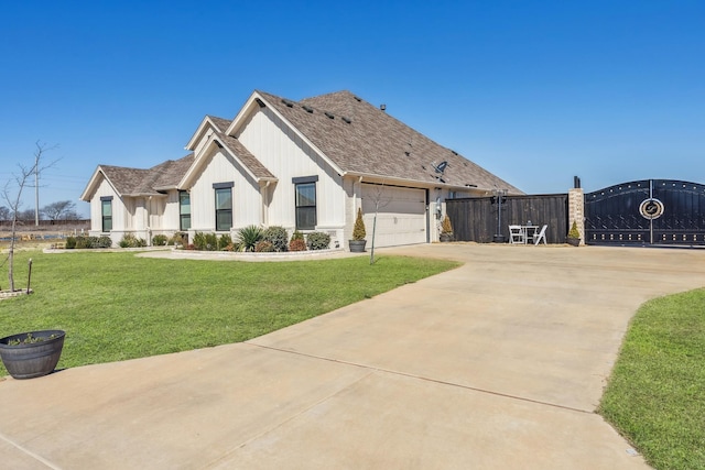 view of front of property with a shingled roof, an attached garage, a front yard, fence, and driveway