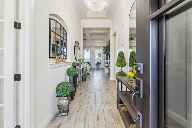 hallway featuring coffered ceiling, light wood-style flooring, beamed ceiling, crown molding, and a notable chandelier