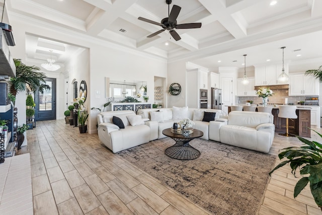 living room with wood finish floors, beamed ceiling, a high ceiling, and visible vents