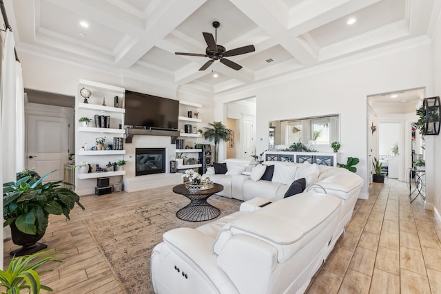 living area with coffered ceiling, beamed ceiling, light wood-type flooring, and a glass covered fireplace