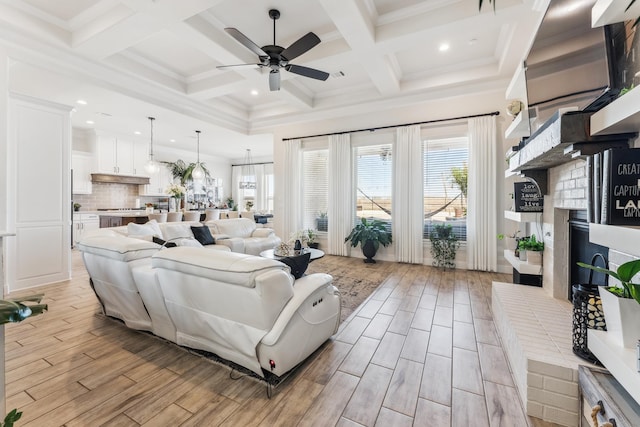 living room featuring wood finish floors, a ceiling fan, a brick fireplace, coffered ceiling, and beamed ceiling