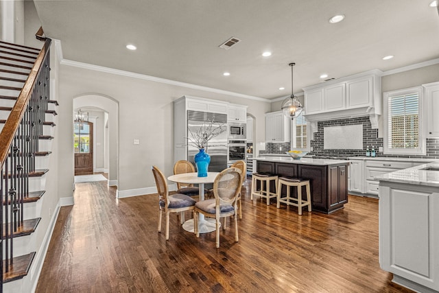 dining space with arched walkways, visible vents, and crown molding