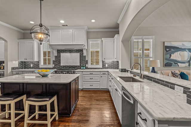 kitchen with dark wood-type flooring, a sink, stainless steel appliances, arched walkways, and white cabinets