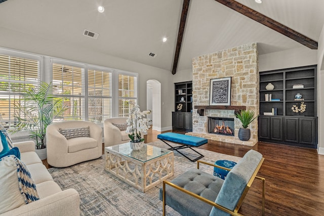 living area featuring visible vents, beam ceiling, wood finished floors, arched walkways, and a fireplace