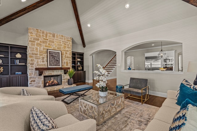 living room featuring stairway, wood finished floors, baseboards, lofted ceiling with beams, and a fireplace