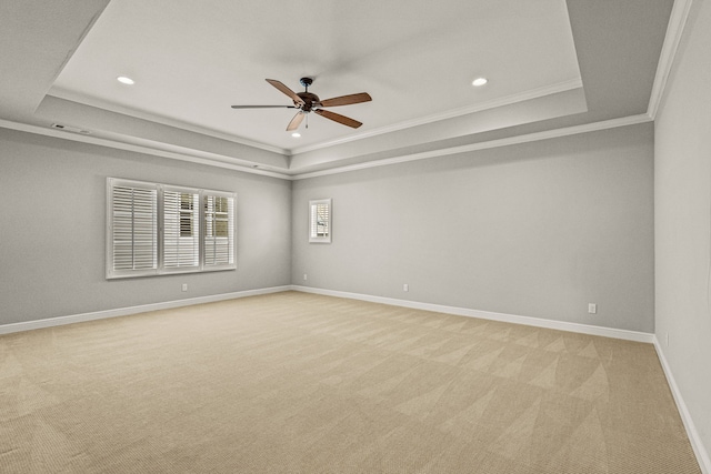 spare room with a raised ceiling, crown molding, baseboards, and light carpet