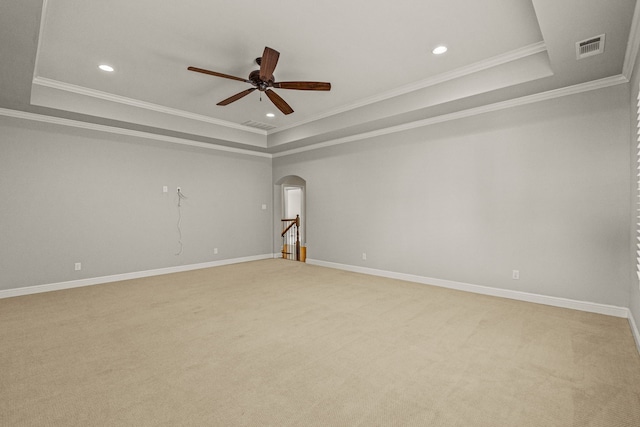 empty room with a raised ceiling, baseboards, arched walkways, and ceiling fan