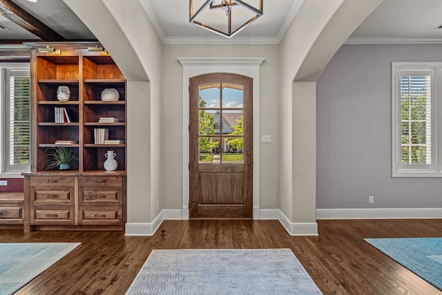 entrance foyer featuring arched walkways, dark wood-type flooring, baseboards, and ornamental molding