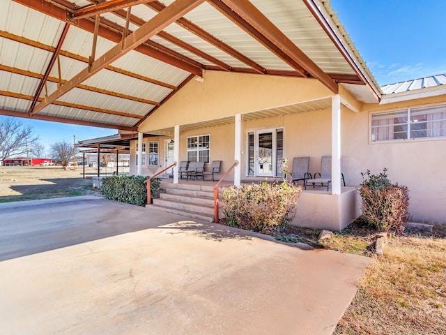 view of front of home featuring a porch, metal roof, and stucco siding