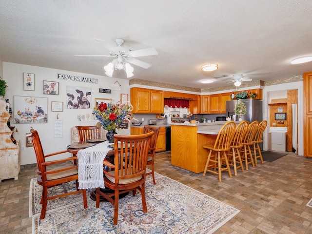 dining space with a textured ceiling, stone finish floor, and a ceiling fan