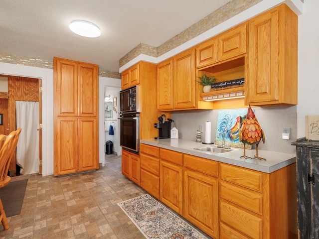 kitchen featuring light countertops, black appliances, and a sink