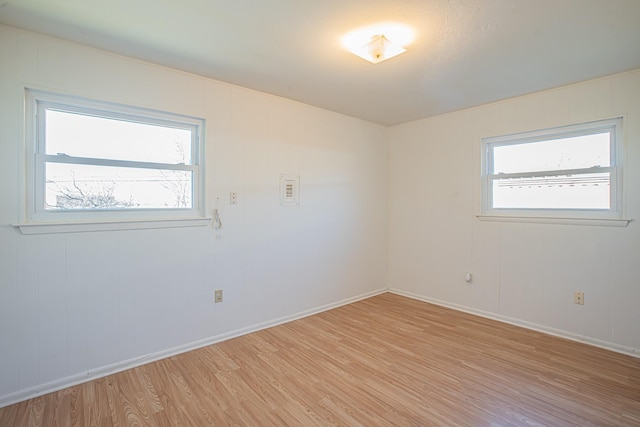 empty room with baseboards, a wealth of natural light, and light wood-style floors