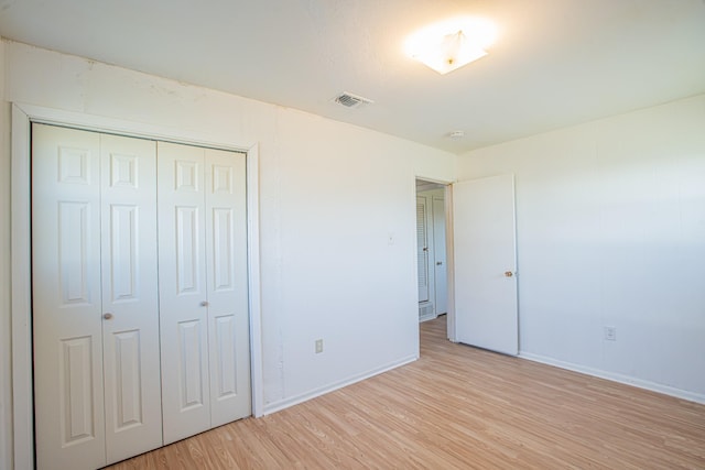 unfurnished bedroom featuring light wood-style floors, a closet, visible vents, and baseboards