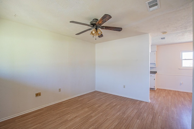 spare room featuring light wood-style floors, visible vents, and a textured ceiling