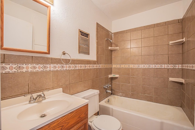 bathroom featuring wainscoting, toilet, shower / bathtub combination, vanity, and tile walls