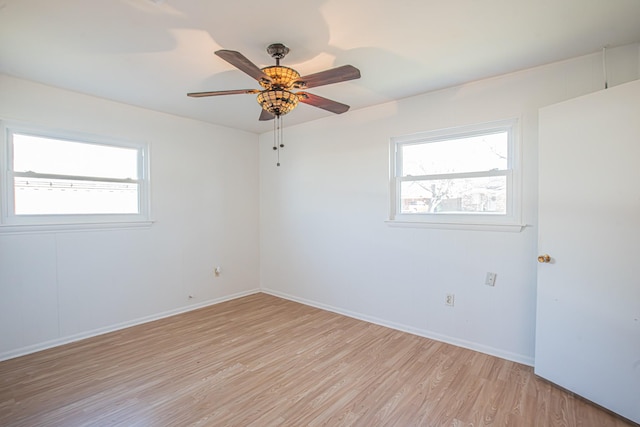 unfurnished room with light wood-style floors, a wealth of natural light, and baseboards